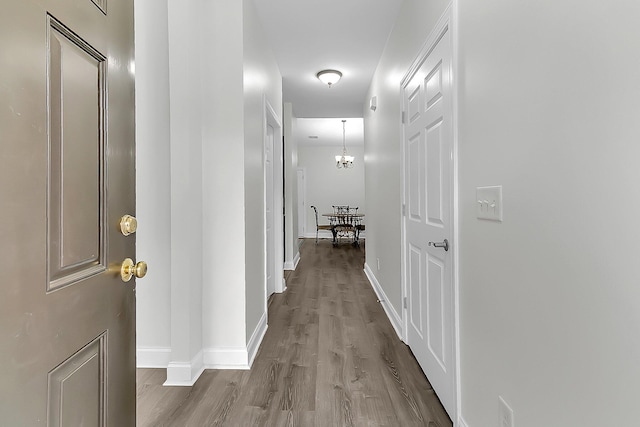 hallway with an inviting chandelier and wood-type flooring