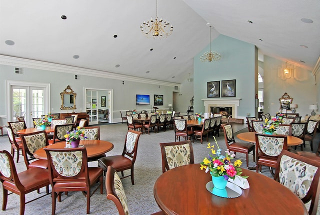 carpeted dining space with ornamental molding, high vaulted ceiling, french doors, and an inviting chandelier