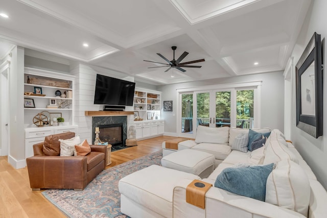 living room with coffered ceiling, ceiling fan, light hardwood / wood-style floors, and a fireplace