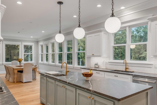 kitchen featuring decorative light fixtures, a kitchen island, dishwasher, and light hardwood / wood-style flooring