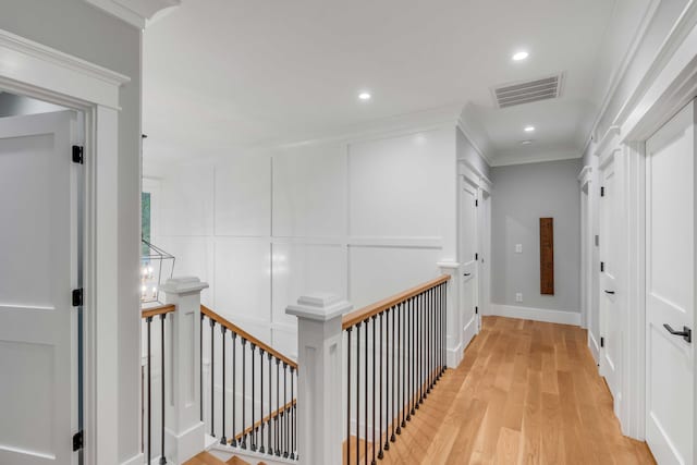 corridor with ornamental molding and light hardwood / wood-style flooring