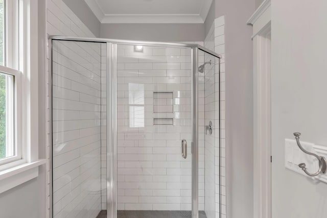 bathroom with a shower with door and ornamental molding