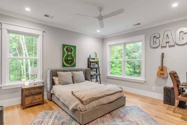 bedroom with ceiling fan, multiple windows, crown molding, and light wood-type flooring