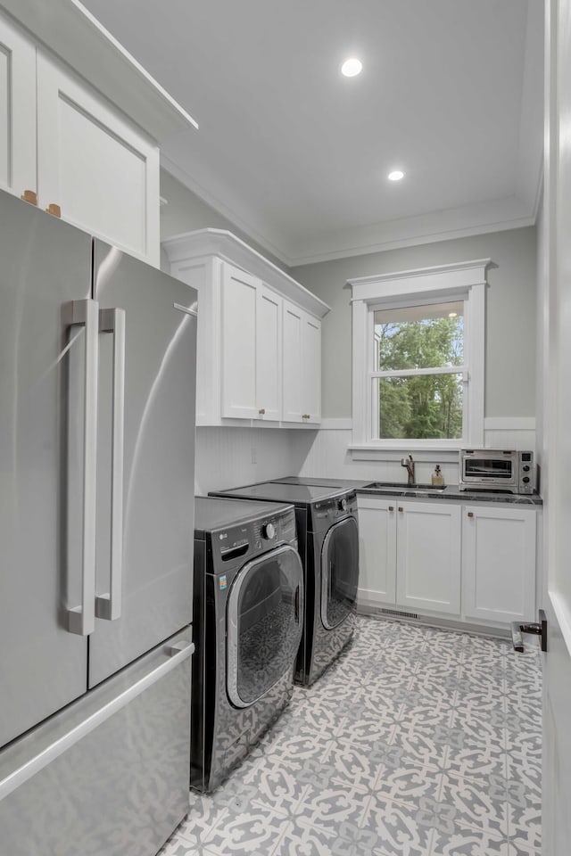 washroom featuring cabinets, ornamental molding, sink, washing machine and dryer, and light tile floors