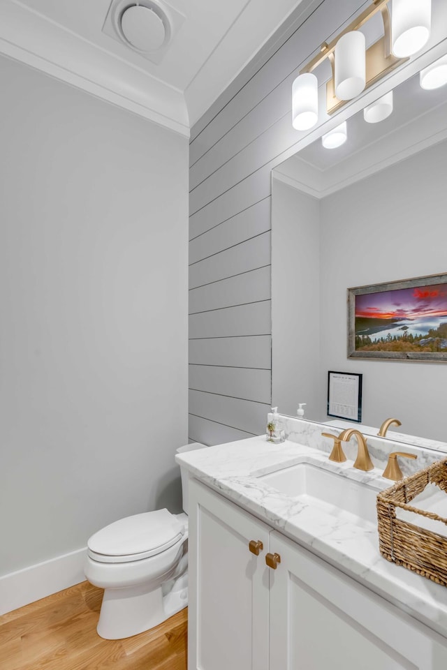 bathroom featuring toilet, vanity, hardwood / wood-style flooring, and ornamental molding