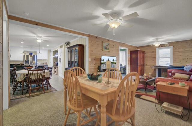 living room featuring wooden walls, carpet, ceiling fan, and a fireplace