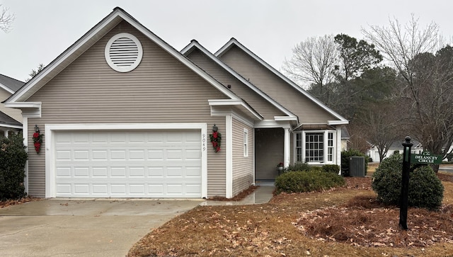 view of front of property with an attached garage, driveway, and cooling unit