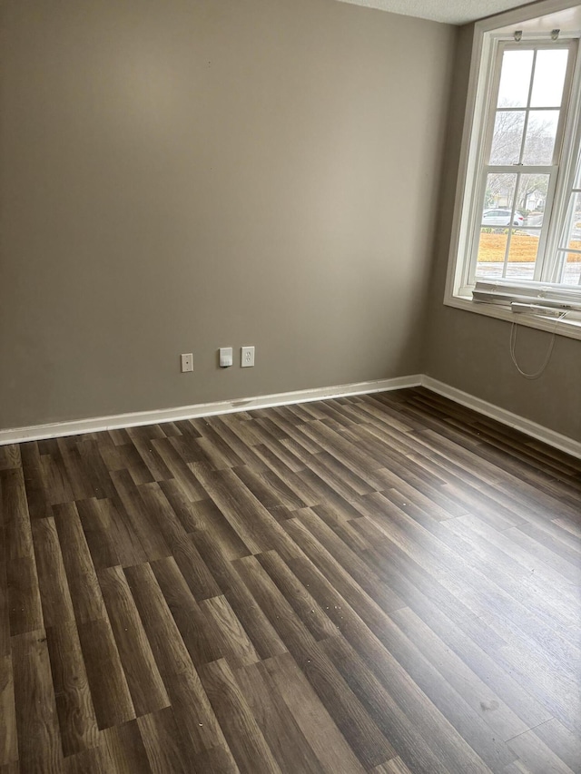 empty room featuring dark wood-style flooring and baseboards