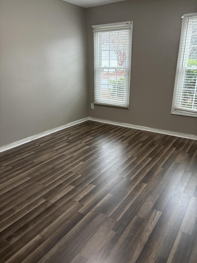 unfurnished room featuring dark wood-style floors and baseboards