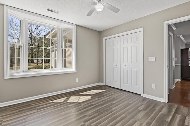 unfurnished bedroom featuring a closet, wood finished floors, visible vents, and baseboards