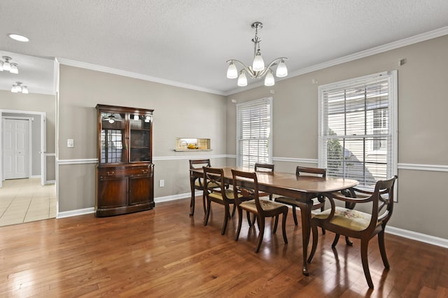 dining room with ornamental molding, a textured ceiling, an inviting chandelier, and wood finished floors