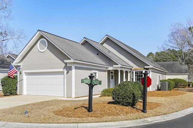 view of front of home with concrete driveway, roof with shingles, an attached garage, and central air condition unit