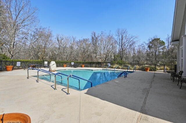 pool with a patio area and fence