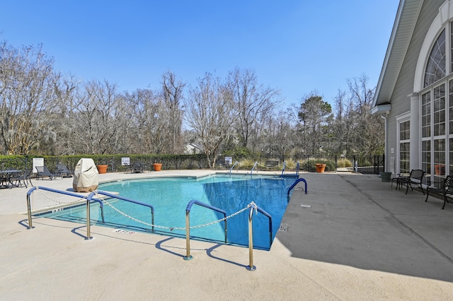 community pool with a patio and fence