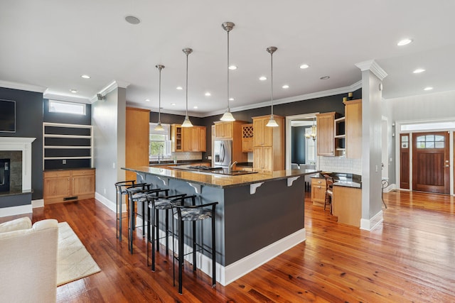 kitchen featuring stainless steel fridge with ice dispenser, dark hardwood / wood-style floors, backsplash, pendant lighting, and a breakfast bar area