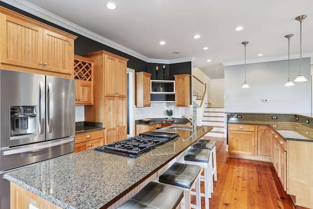 kitchen featuring a large island with sink, stainless steel fridge, dark stone counters, and light wood-type flooring