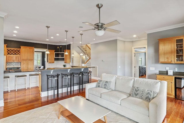 living room featuring ceiling fan, ornamental molding, and light wood-type flooring