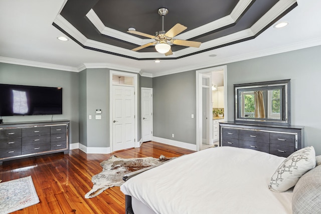 bedroom featuring ceiling fan, a raised ceiling, dark hardwood / wood-style floors, crown molding, and ensuite bathroom