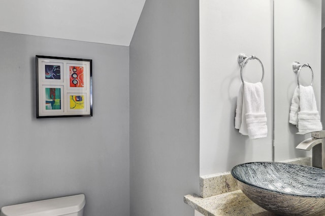 bathroom with vaulted ceiling, toilet, and sink