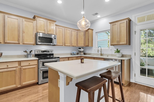 kitchen with sink, stainless steel appliances, light hardwood / wood-style floors, a breakfast bar, and ornamental molding