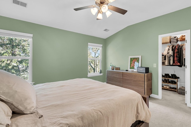 carpeted bedroom featuring a spacious closet, vaulted ceiling, multiple windows, and ceiling fan