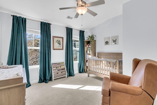 bedroom with lofted ceiling, ceiling fan, light colored carpet, and a crib