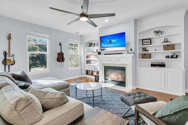 living room featuring wood-type flooring, ceiling fan, and built in shelves