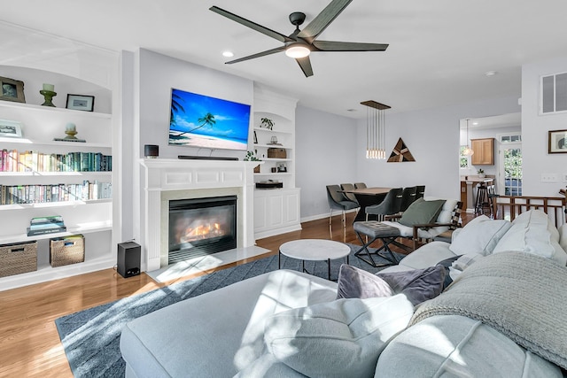 living room featuring ceiling fan, hardwood / wood-style floors, and built in features