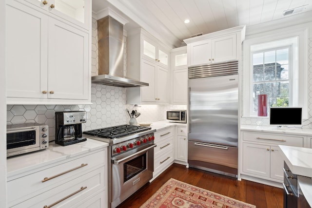 kitchen featuring dark wood-type flooring, wall chimney exhaust hood, white cabinetry, high quality appliances, and light stone countertops