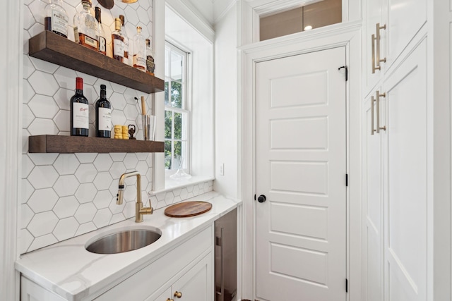 bar featuring white cabinetry, sink, and tasteful backsplash