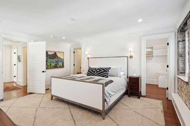 bedroom with crown molding, a spacious closet, hardwood / wood-style floors, and a closet