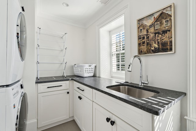 kitchen featuring stacked washer / dryer, sink, white cabinets, ornamental molding, and kitchen peninsula