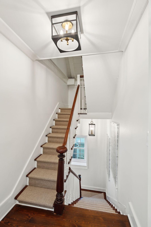 stairway with hardwood / wood-style flooring, lofted ceiling, and crown molding