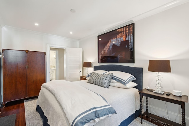 bedroom featuring crown molding, ensuite bath, and dark hardwood / wood-style flooring