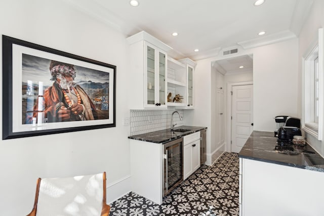 kitchen featuring white cabinetry, sink, ornamental molding, and beverage cooler