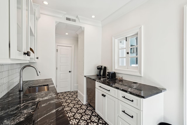 kitchen with sink, dark stone countertops, ornamental molding, white cabinets, and backsplash