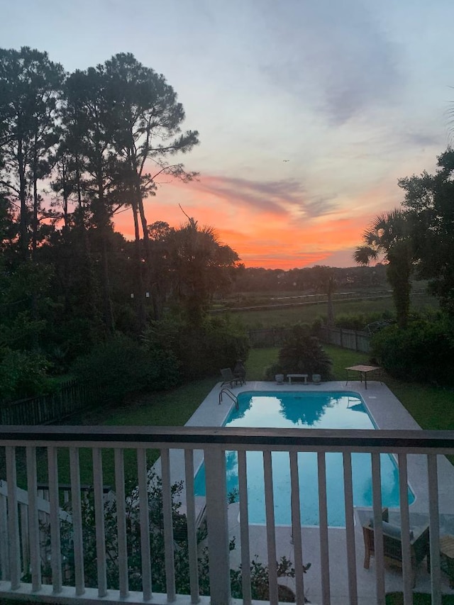 pool at dusk featuring a lawn