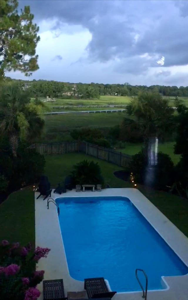 view of swimming pool with a rural view and a lawn