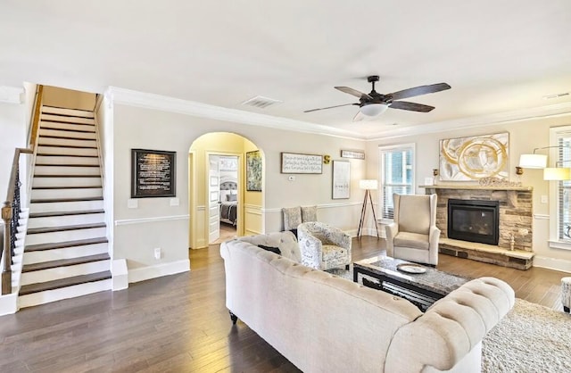 living room with a fireplace, crown molding, dark hardwood / wood-style floors, and ceiling fan