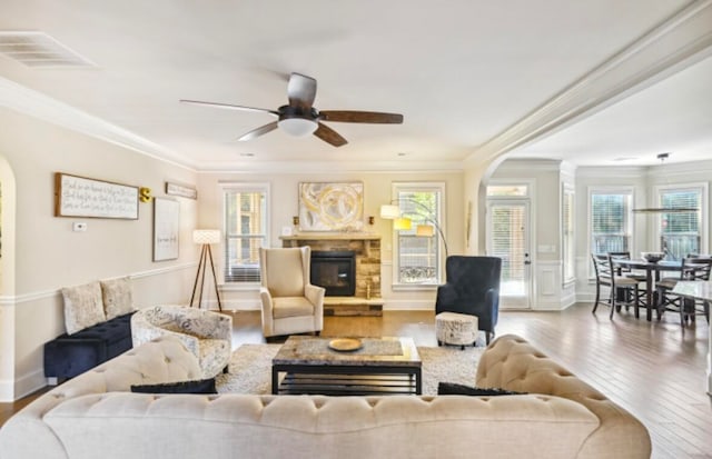 living room with a stone fireplace, light hardwood / wood-style floors, and a wealth of natural light