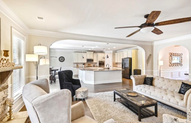 living room featuring crown molding, ceiling fan, sink, and light hardwood / wood-style flooring