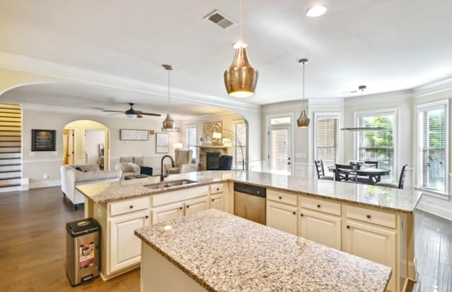 kitchen featuring stainless steel dishwasher, a center island, decorative light fixtures, and sink