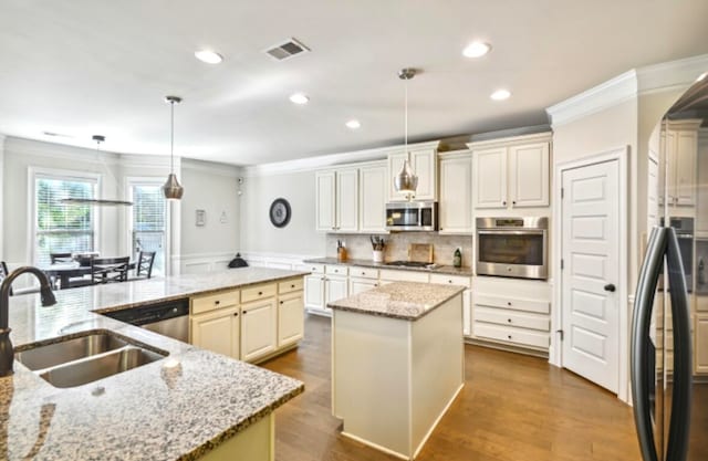 kitchen with hanging light fixtures, a kitchen island with sink, appliances with stainless steel finishes, and sink