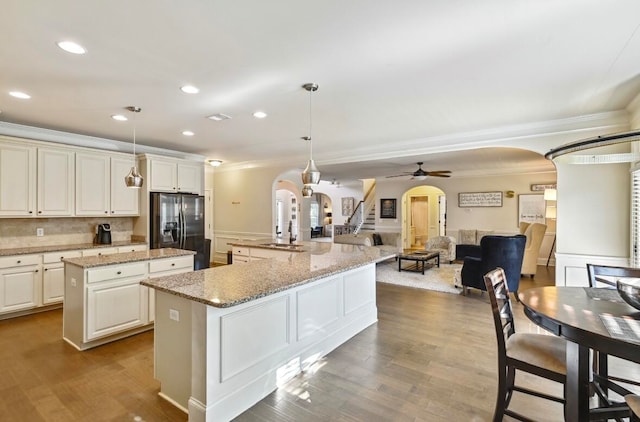 kitchen with stainless steel fridge, ceiling fan, light wood-type flooring, a center island, and pendant lighting