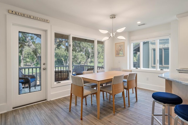 dining room with baseboards, visible vents, an inviting chandelier, and wood finished floors