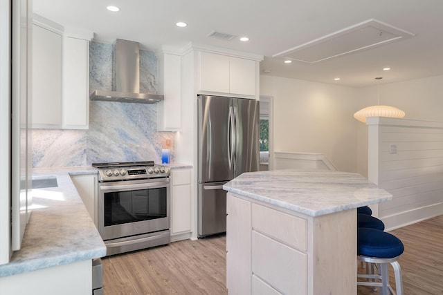 kitchen with a kitchen breakfast bar, light wood-style flooring, wall chimney exhaust hood, stainless steel appliances, and modern cabinets