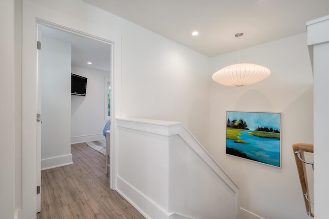 hallway with recessed lighting, wood finished floors, and an upstairs landing