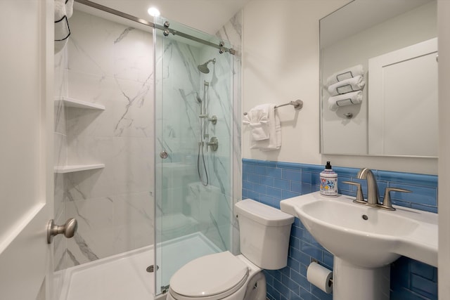 bathroom with toilet, tile walls, wainscoting, and a marble finish shower