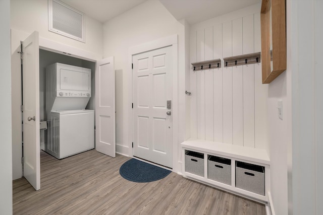 mudroom with light wood-type flooring, stacked washer / dryer, and visible vents