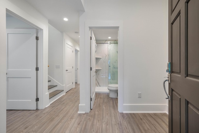 bathroom featuring baseboards, a marble finish shower, wood finished floors, and toilet